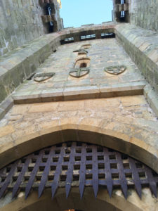 Family coats of arms above the the original iron portcullis at the main gate house.