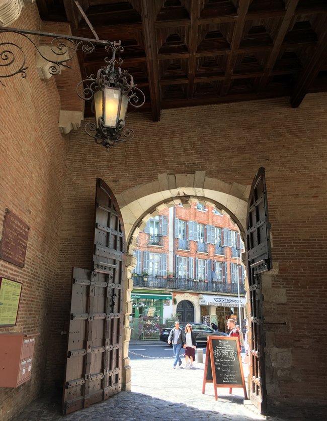 Living history looking out of the immense doors to the courtyard of the 16th century Hotel d'Assezat.